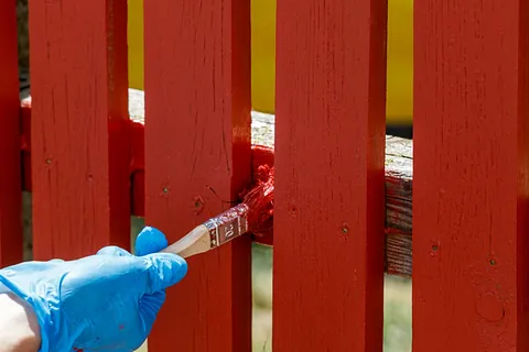 Gjerde blir malt med rødmaling